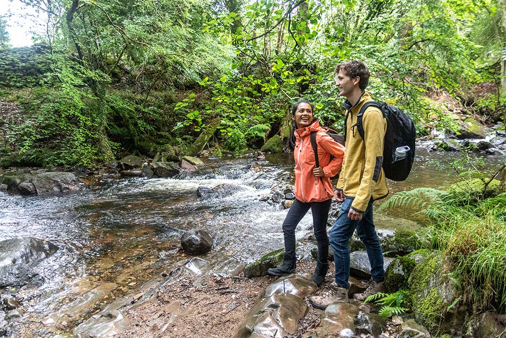 Couple looking at river in wooded East Okement Valley